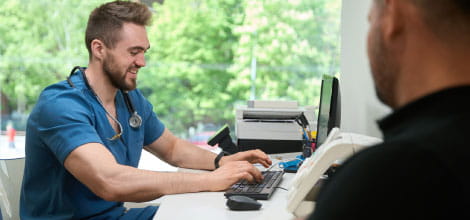 Doctor entering patient's data onto a desktop during consultation